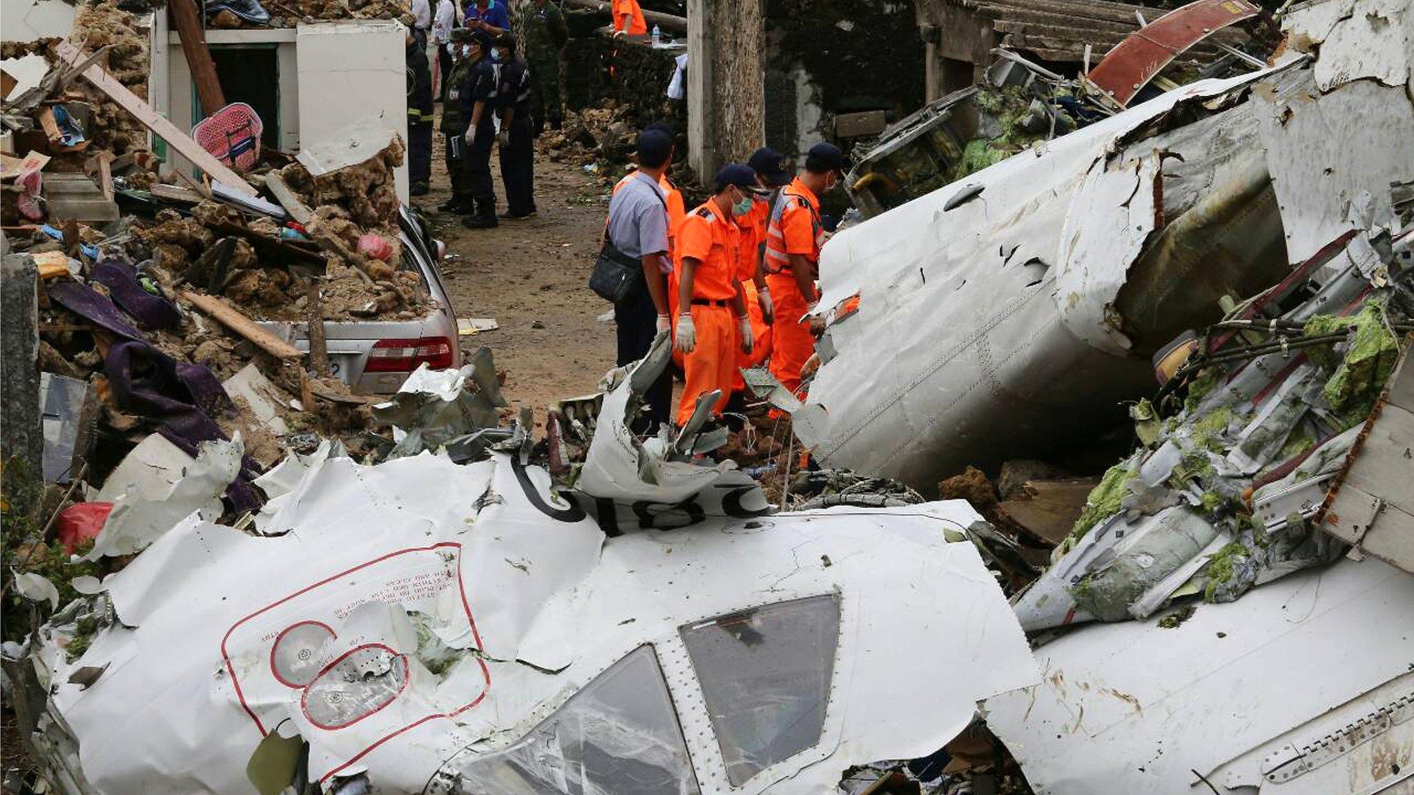 Rescue workers survey the wreckage of TransAsia Airways Flight GE222 on the Taiwanese island of Penghu on 24 July 2014