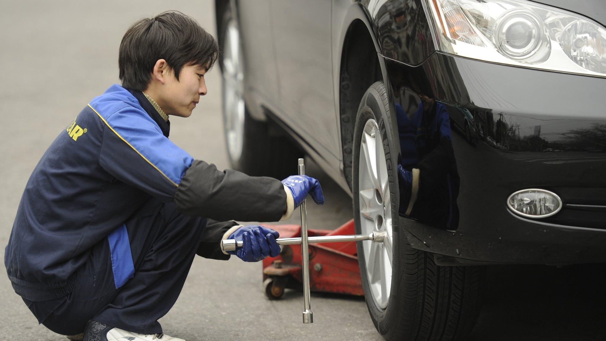 A worker at an auto shop changes the tyres on a car in Shanghai