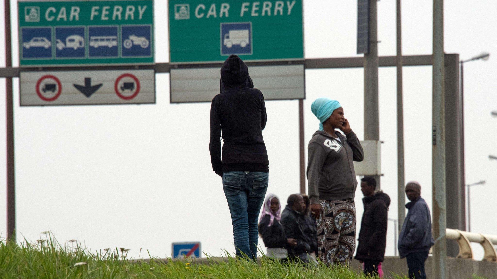 Migrants wait by side of road near Calais ferry port on 5 September 2014