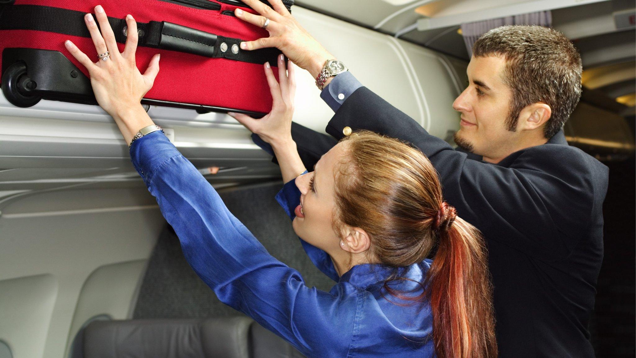 passengers put bags in overhead lockers