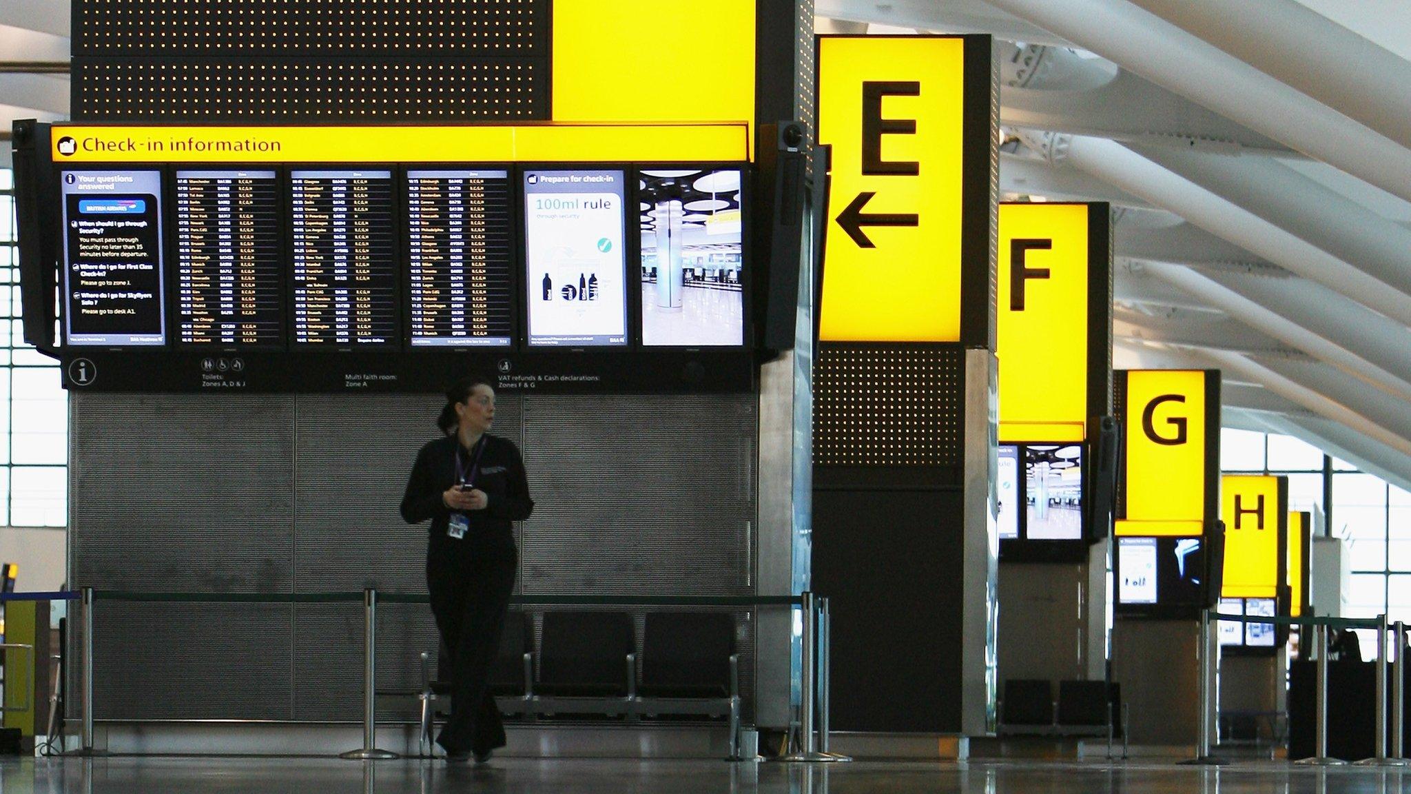 A member of staff stands in the Check-In area of Terminal 5 at Heathrow