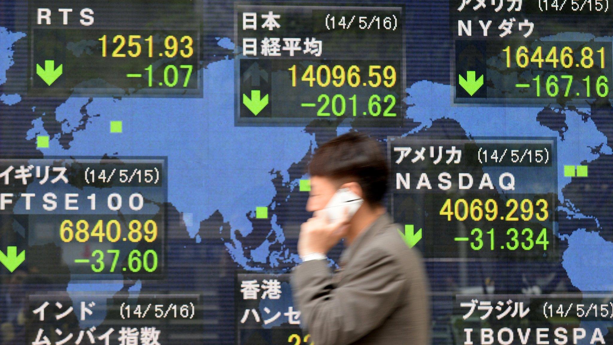 A man walks past an electronic stock indicator in Tokyo.