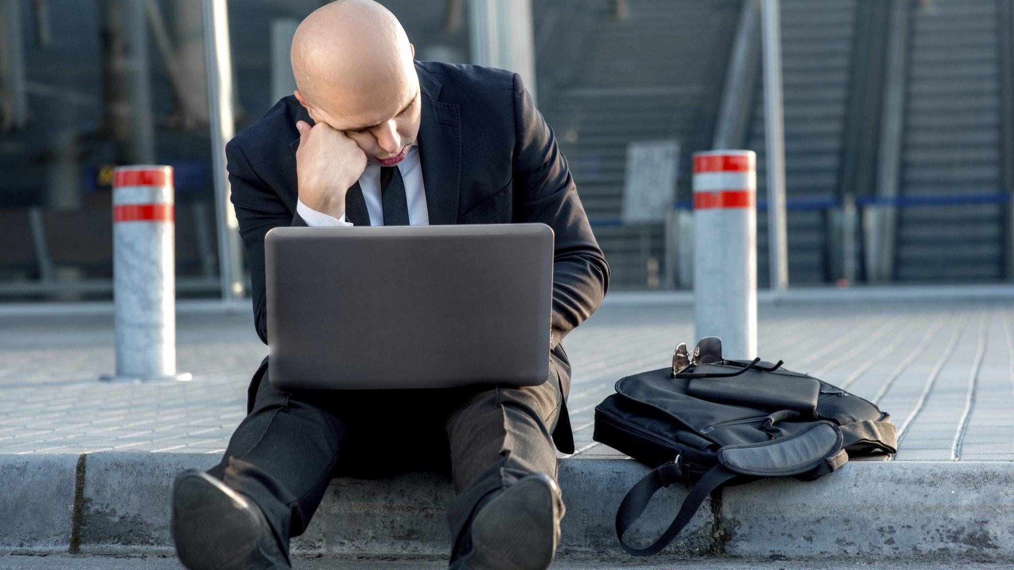 Man on curb with laptop