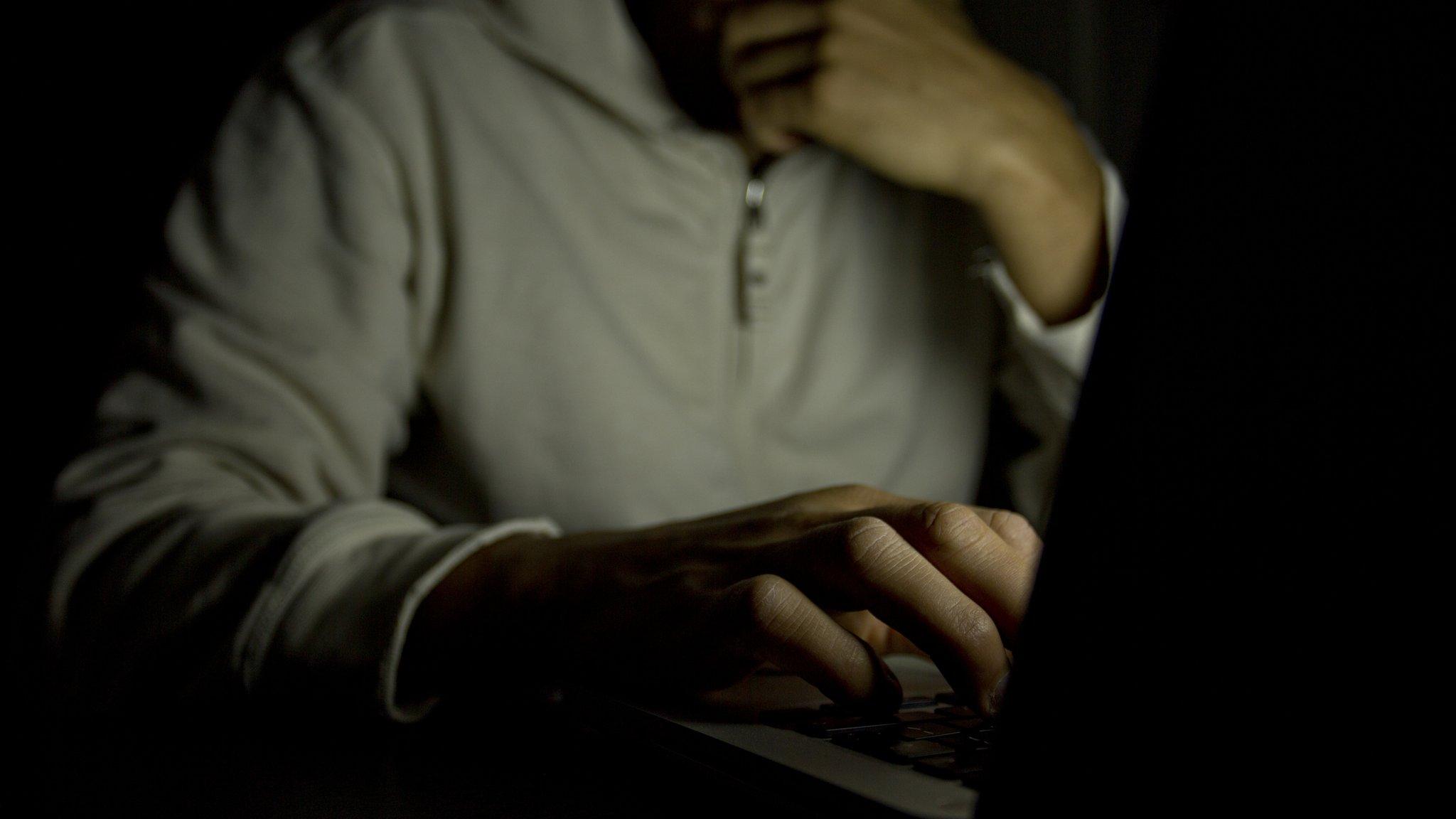 A figure behind a computer screen
