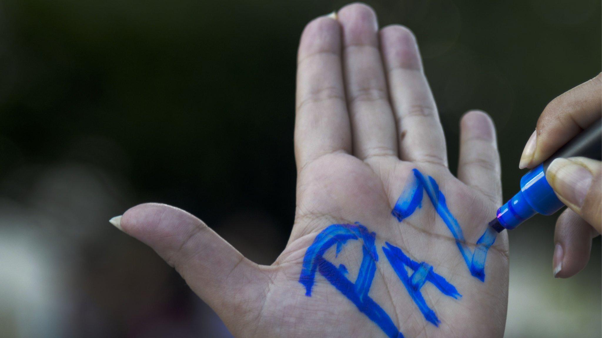 A woman writes the word 'Peace' on the palm of her hand during a demonstration in Medellin on 11 June, 2014