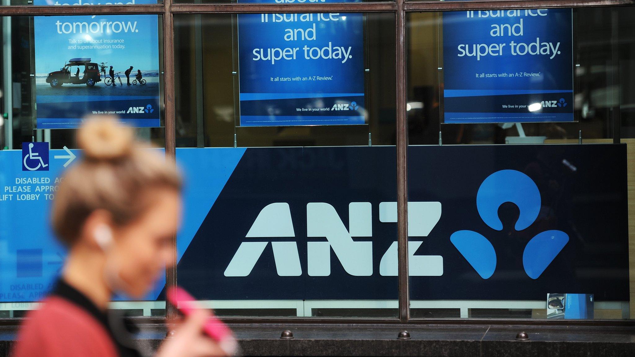 A woman walks past Australia and New Zealand Banking Group (ANZ) signage displayed