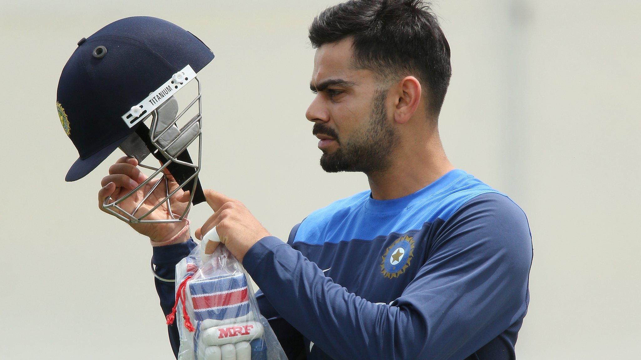 Player inspects cricket helmet