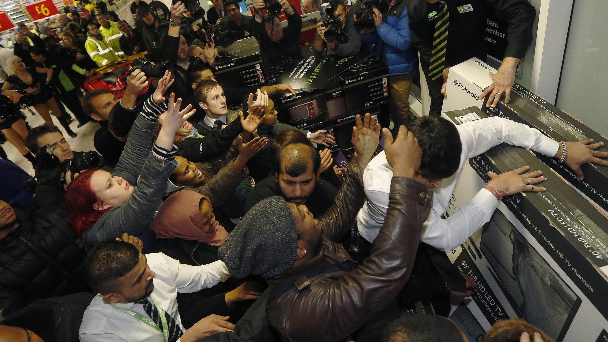 People in a shop pushing to get to televisions