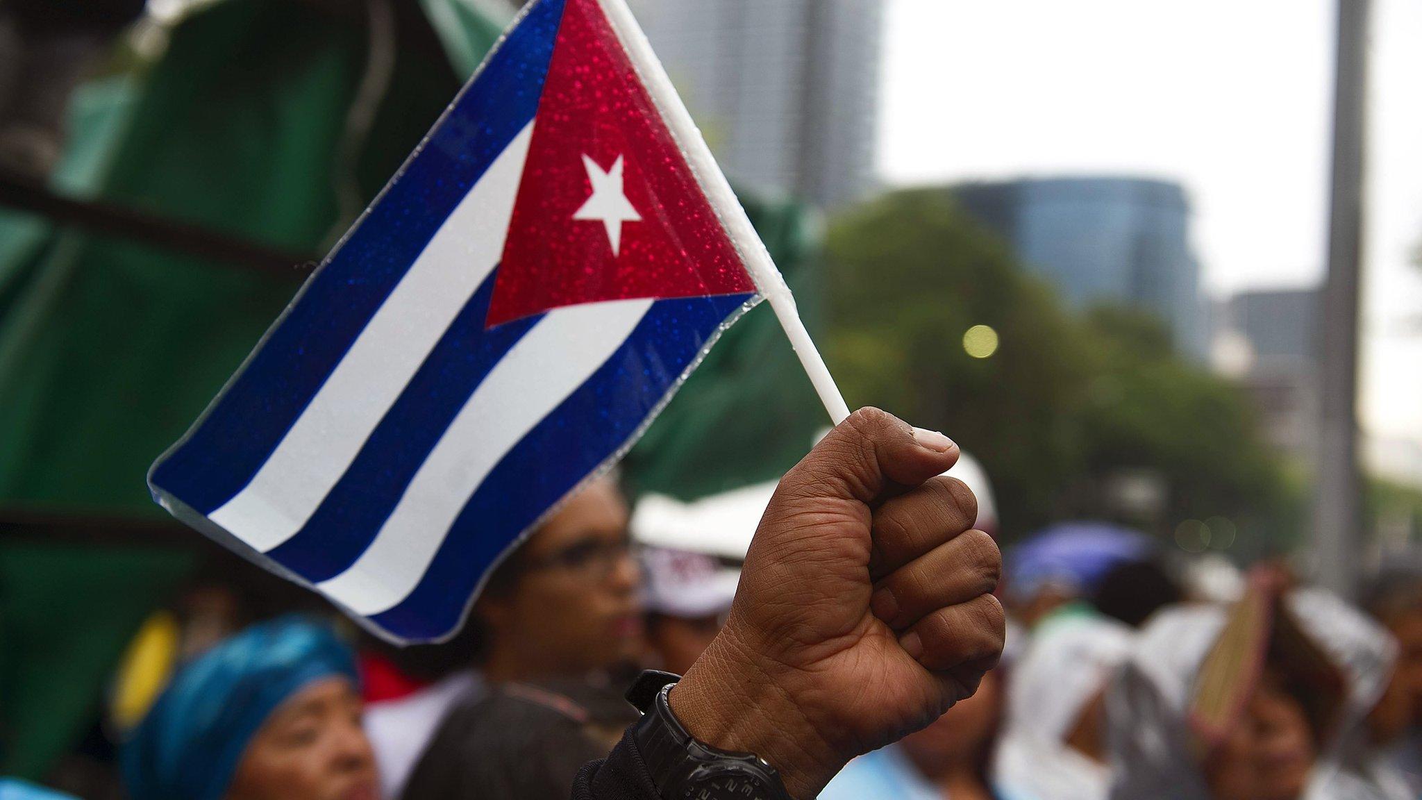 A man raises his fist with a Cuban flag in Mexico City on 26 July 2011