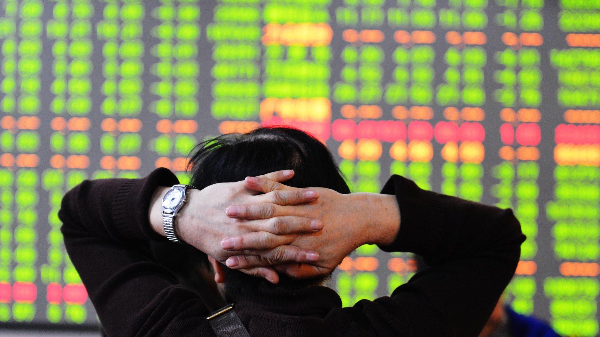 A man looking at a board of Chinese shares