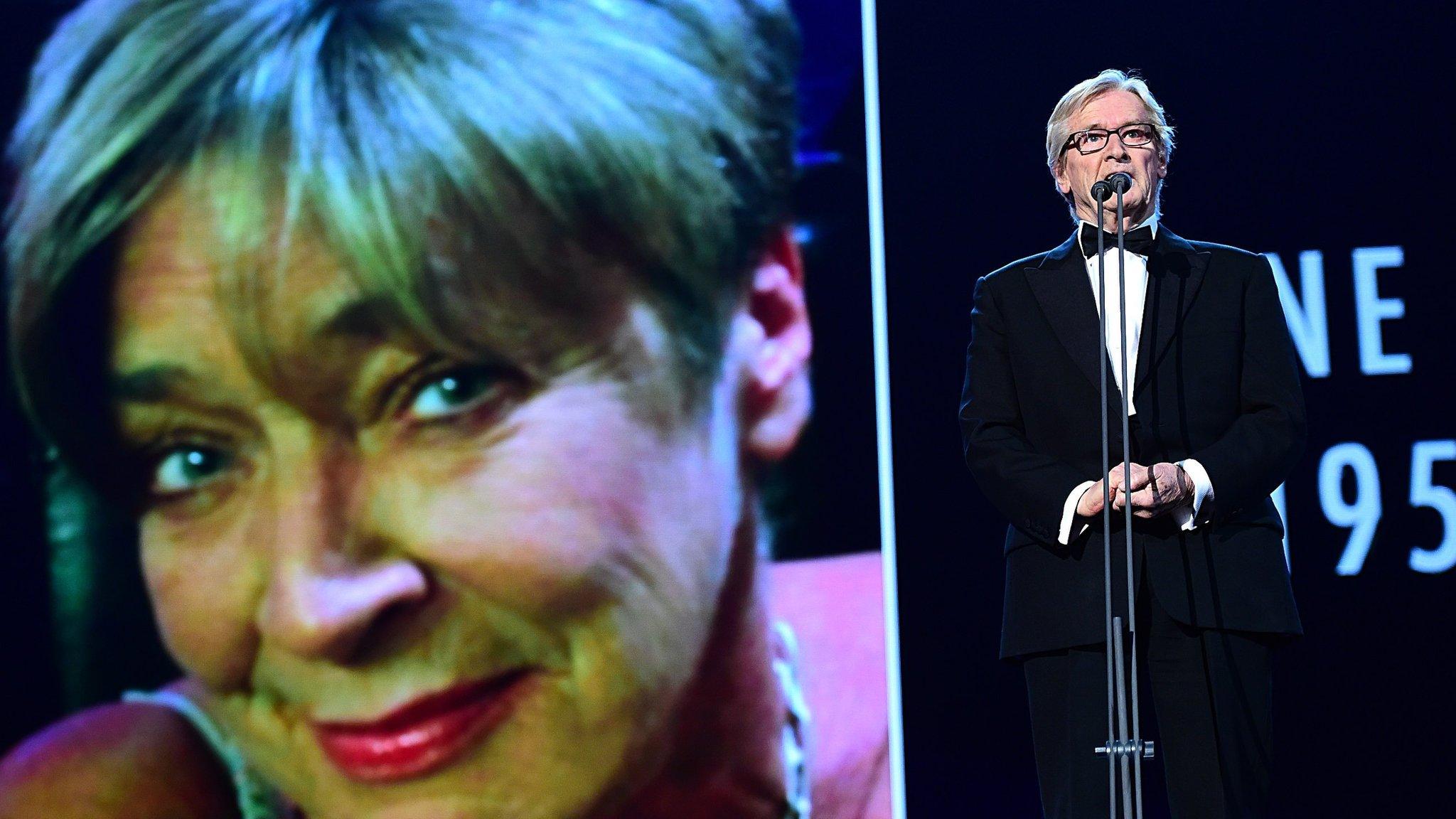 William Roache standing in front of a picture of Anne Kirkbride