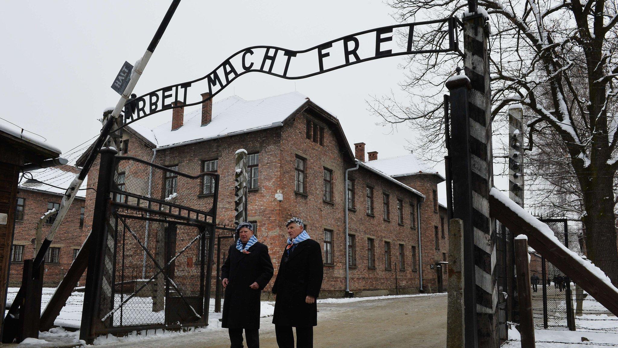 Holocaust survivors walk through the gate of the former Auschwitz concentration camp on 27 January 2015