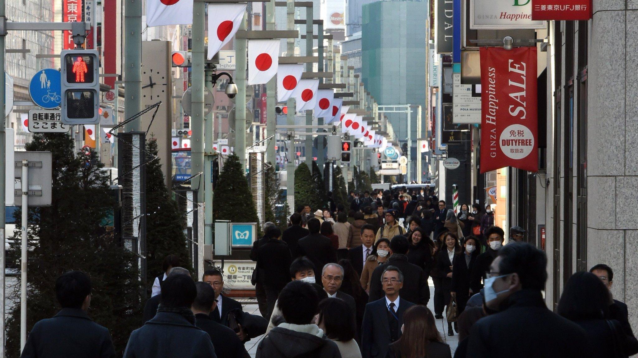 Shoppers walk down a busy street in the Ginza shopping district in central Tokyo