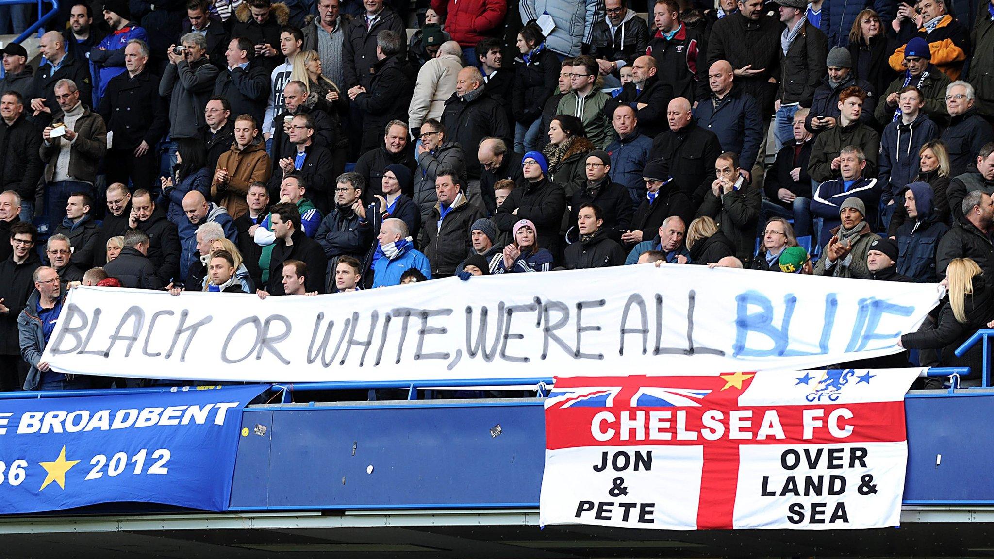 Fans holding a banner reading: "Black or white, we're all blue."