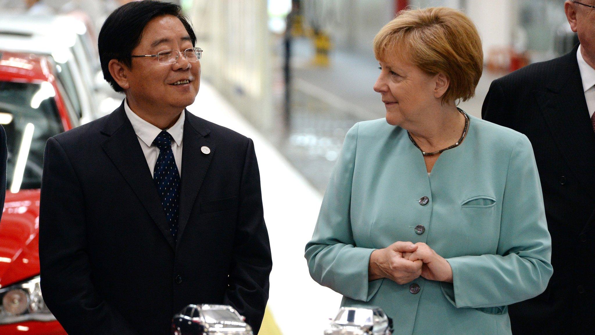 German Chancellor Angela Merkel (R) stands with FAW Group CEO Xu Jianyi