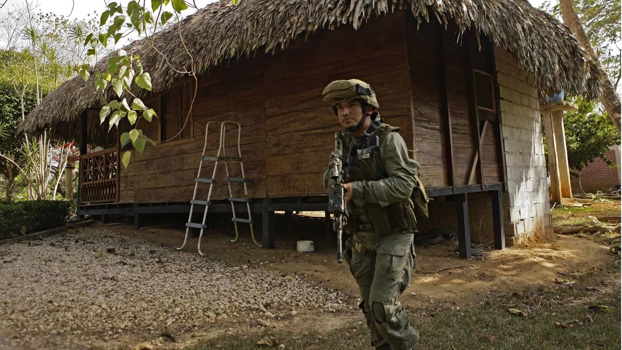 Colombian policeman in front of a hut used by Dairo Antonio Usuga as a hide-out