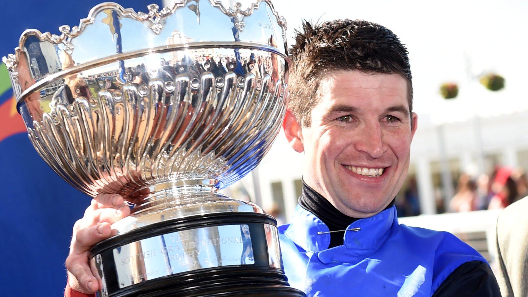 Jockey Robbie Dunne shows off his huge prize after clinching victory in the Scottish Grand National