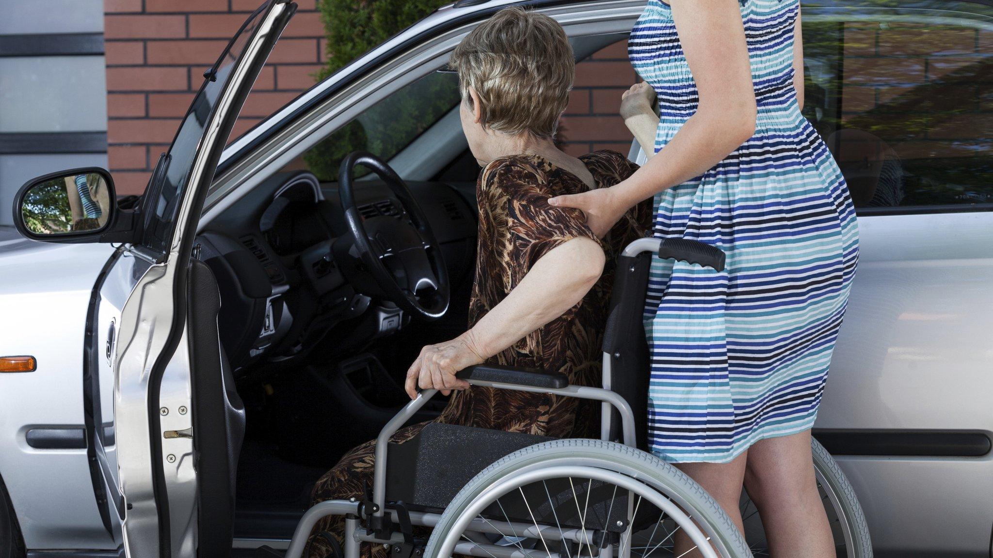 Carer helping woman into car