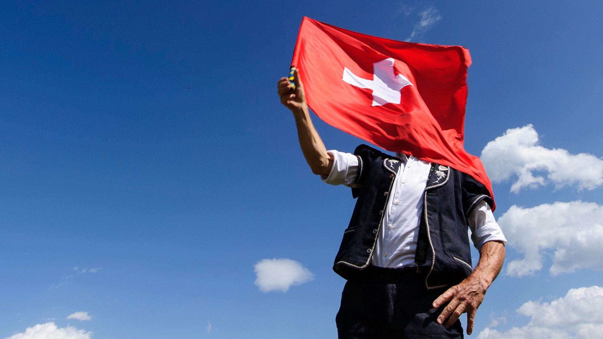 A man holding a Swiss flag in Nendaz, Switzerland.