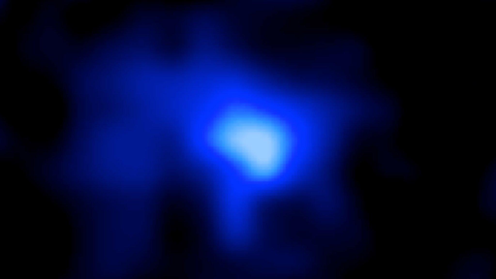 An image of a far away galaxy captured by astronomers. The galaxy appears as a bright blue flare against the blackness of space.