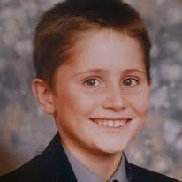 A school portrait of a boy around 12 years old in a black blazer and grey shirt. He has brown eyes and brown hair.