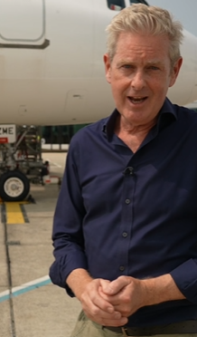 A man in a blue shirt stands in front of an Easyjet plane.