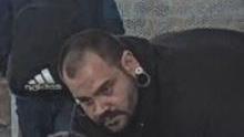 A man with stretchers in his ears with dark receding hair and a beard