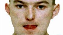 A police mugshot of Thomas Park, who has short brown hair and whose tongue is pressed against his upper lip