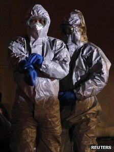 Officials in protective gear stand next to people from the evacuation area near the Fukushima Daini nuclear plant, in Koriyama, 13 March 2011