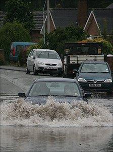 A car driving through a flooded section of road in Wrexham