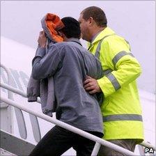 A failed asylum seeker being escorted onto a plane for removal from the UK