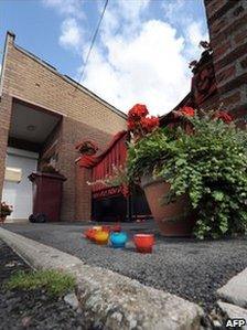 Candles stand on the street outside the house where six babies' remains were found in Villers-au-Tertre, France, 29 July