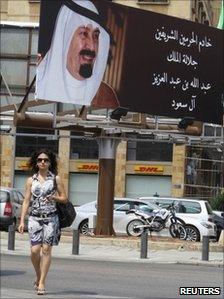 A woman walks past a billboard praising Saudi Arabia's King Abdullah