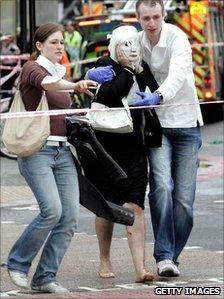 Davinia, her face covered in with a gauze mask, is helped by Paul Dadge and another volunteer who carries Davinia's shoes and jacket