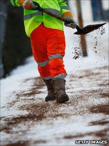 Council worker gritting a pavement