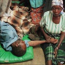 A woman in Malawi holds the hand of a relative with HIV