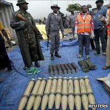 Security officials stand around some of the illegal weapons found at Nigeria's main seaport in Lagos on 27 October 2010