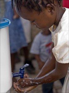 A young girl is properly washing her hands at health clinic in Gaston Margron.