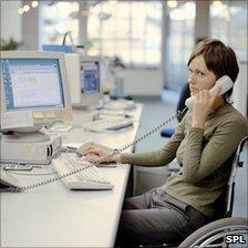 Woman (model) in wheelchair at desk