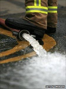 Firefighter's boot on a hose pumping flood water