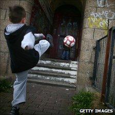 Two young boys play football in a rundown street in Glasgow