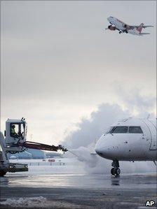 An aircraft takes off as another is de-iced at Copenhagen's Kastrup International Airport, 21 December 2010
