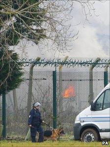 A prison officer patrols the Ford perimeter fence