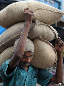 A labourer carries sacks of food grains in India