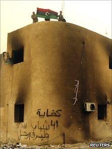 Libyan protesters display the country's pre-Gaddafi flag on top of a building during a demonstration in the seaport city of Tobruk, 20 February 2011