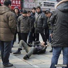 Unidentified men surround a foreign journalist after they pushed him to the ground in Wangfujing, Beijing, 27 February