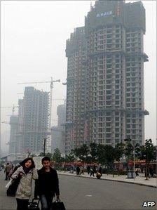 Pedestrians pass a property construction site in Chongqing