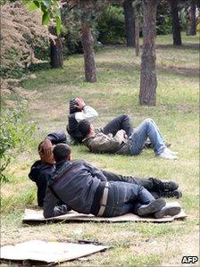 Tunisian migrants lie on grass in a park near the Porte de la Villette, northern Paris