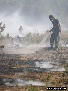 Firefighters damp down smouldering undergrowth in Swinley Forest