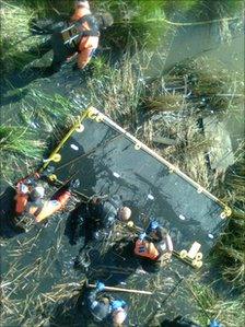 Police searching the marsh land with a raft